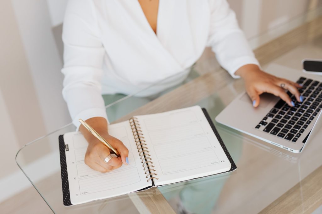 woman with hands on a computer and an agenda